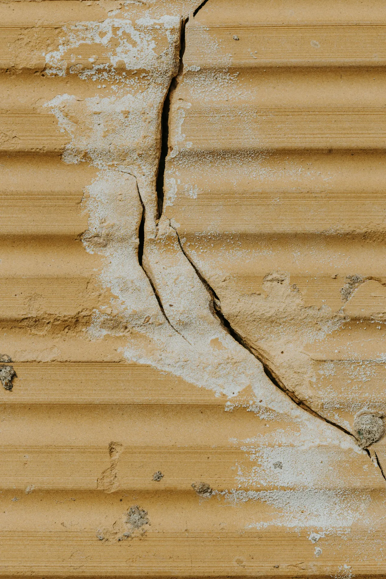 Cracked ochre wall texture with rough mineral marks.