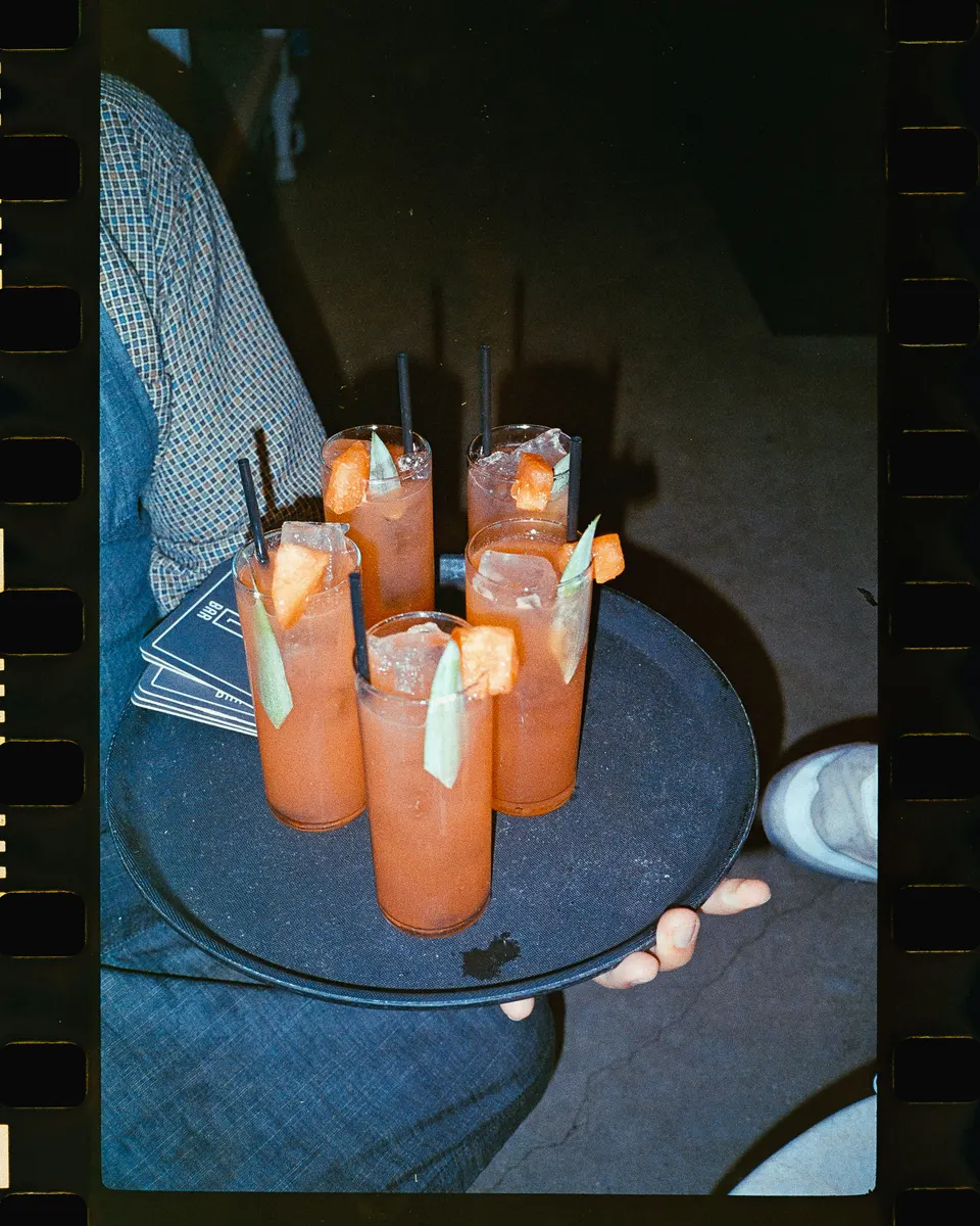 Tray of bright drinks photographed with direct flash at night.
