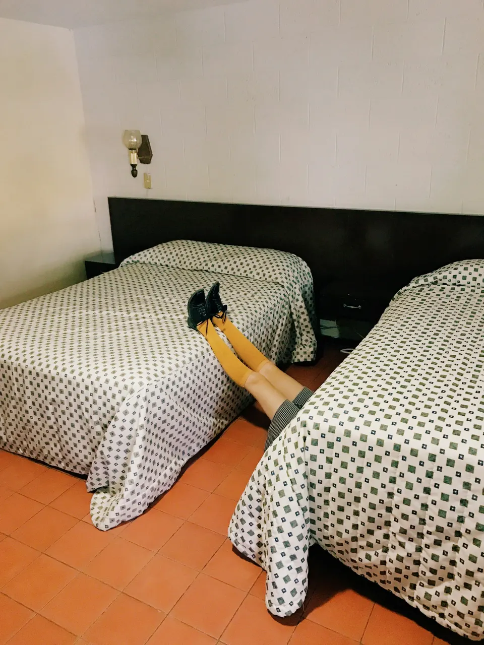 Two single beds in a simple tiled room.